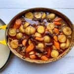 aerial view of beef stew in large dutch oven with carrots, potatoes, and msuhrooms.