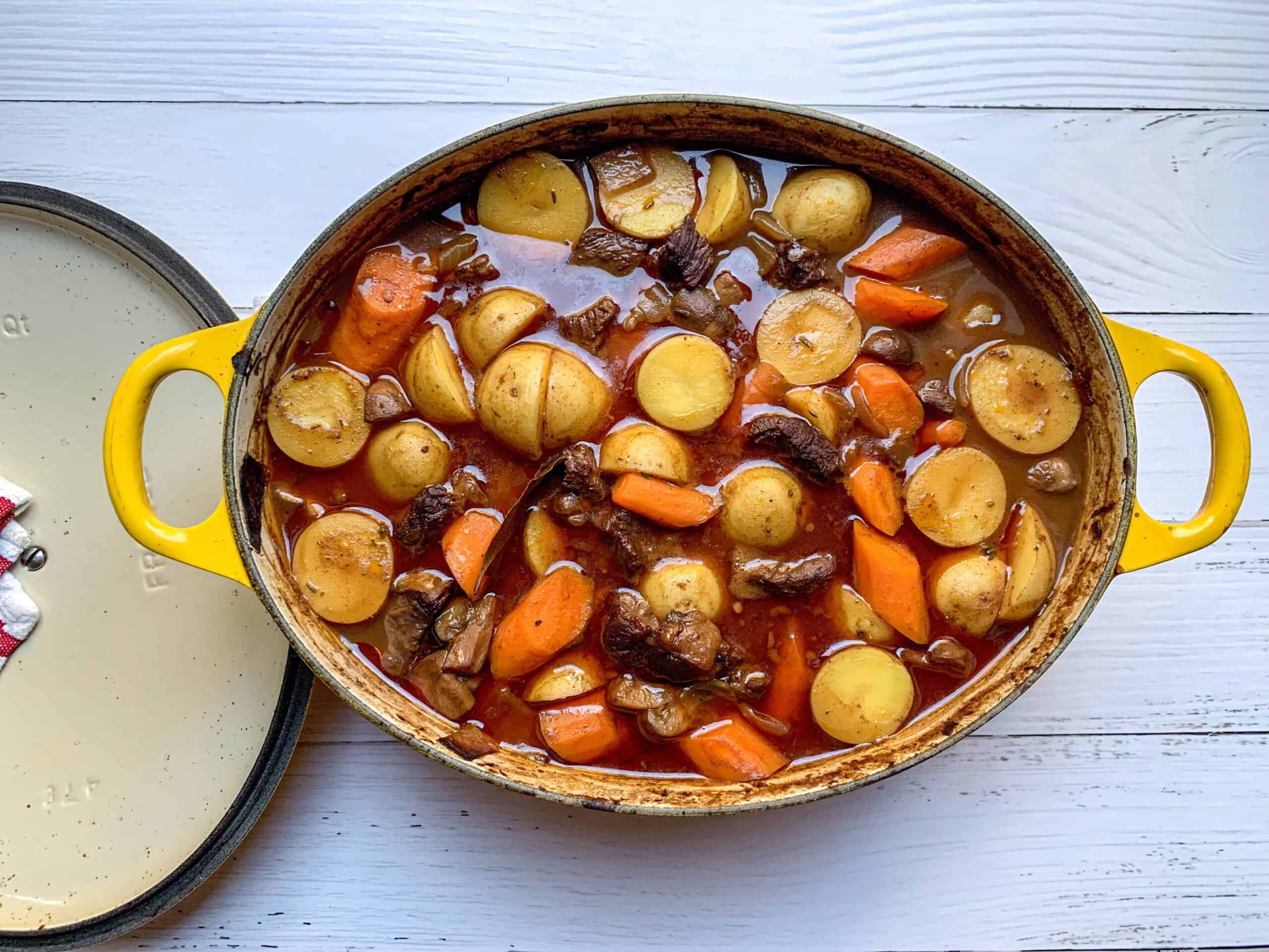 aerial view of beef stew in large dutch oven with carrots, potatoes, and msuhrooms.