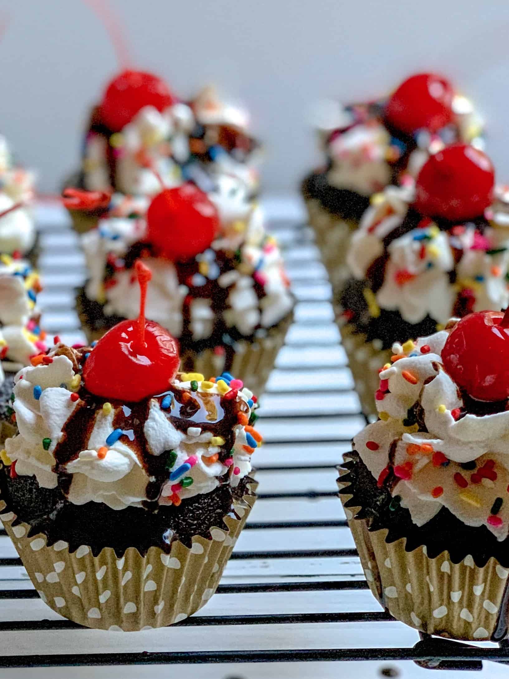 close up picture of hot fudge sundae cupcakes with cherry on top