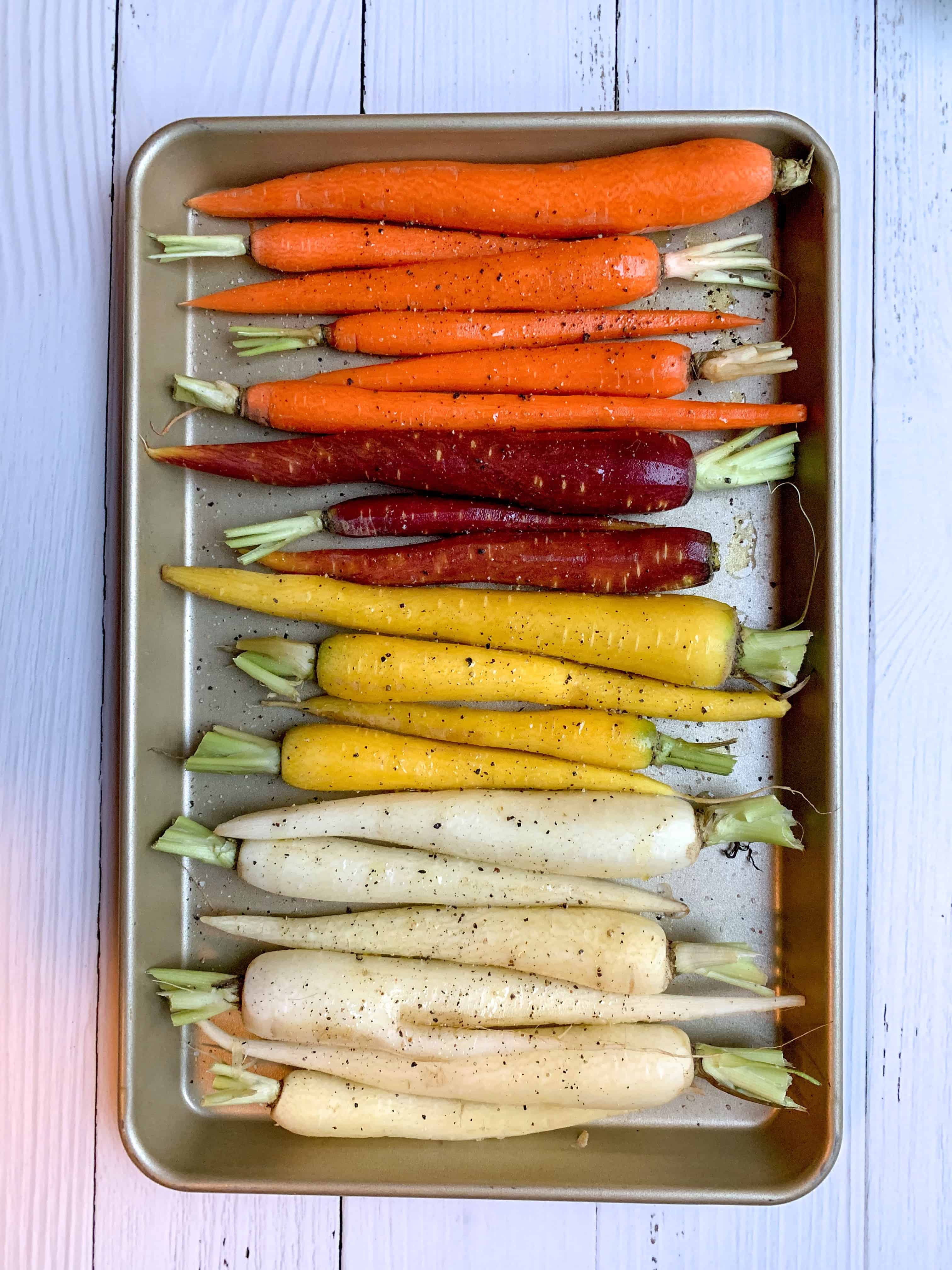 rainbow carrots on a baking sheet with salt, pepper, and olive oil 