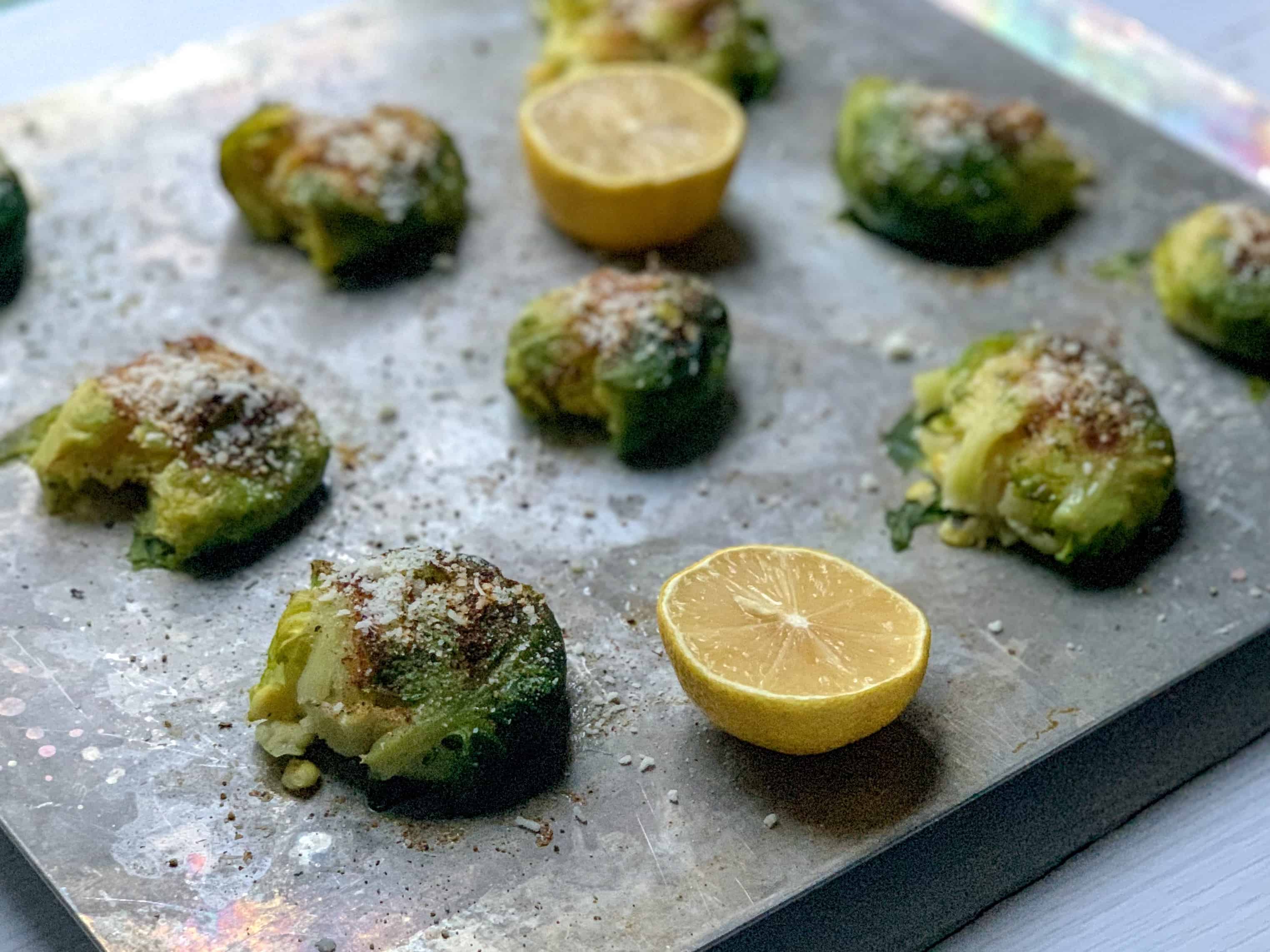 side view of roasted brussels sprouts with lemon halves. 