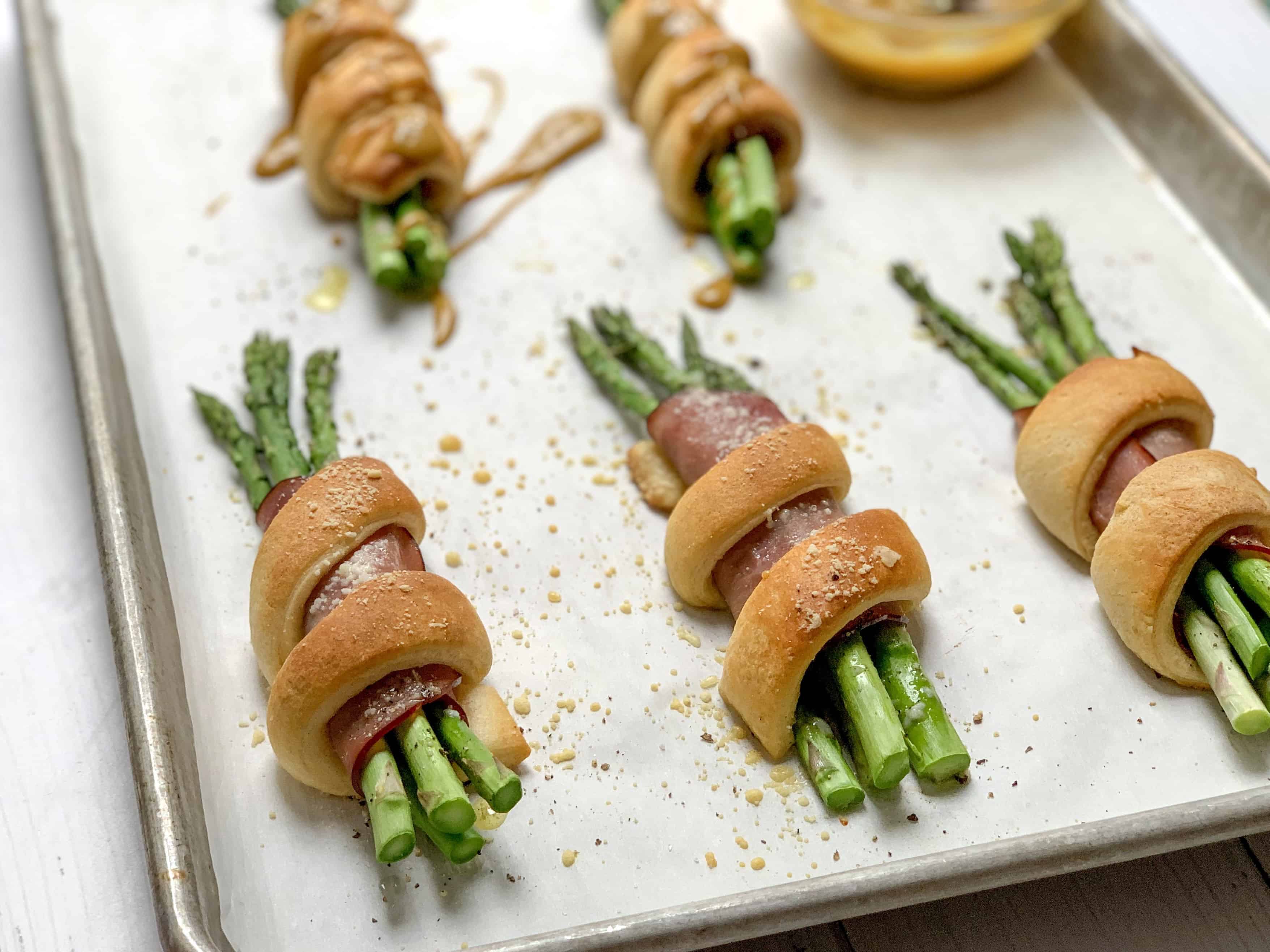 side shot of freshly baked wrapped asparagus and ham bundles with fresh parmesan on top. 