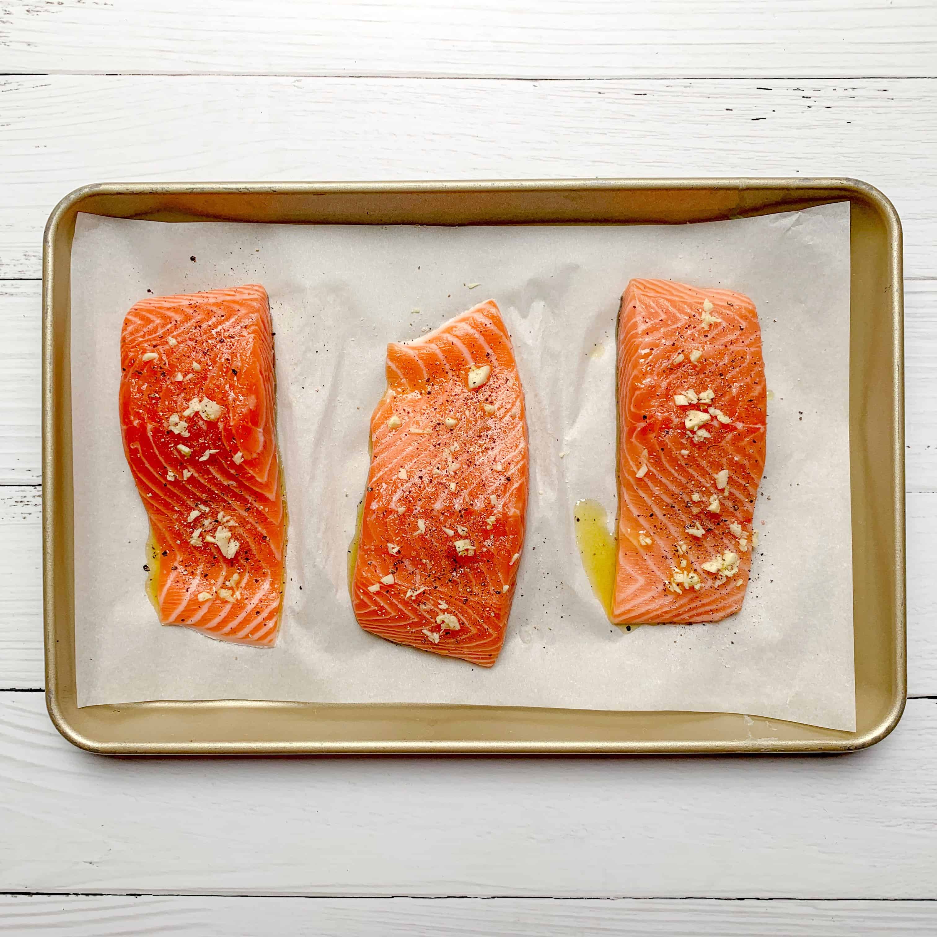 3 big hunks of salmon fillets ready to be cooked on baking sheet 