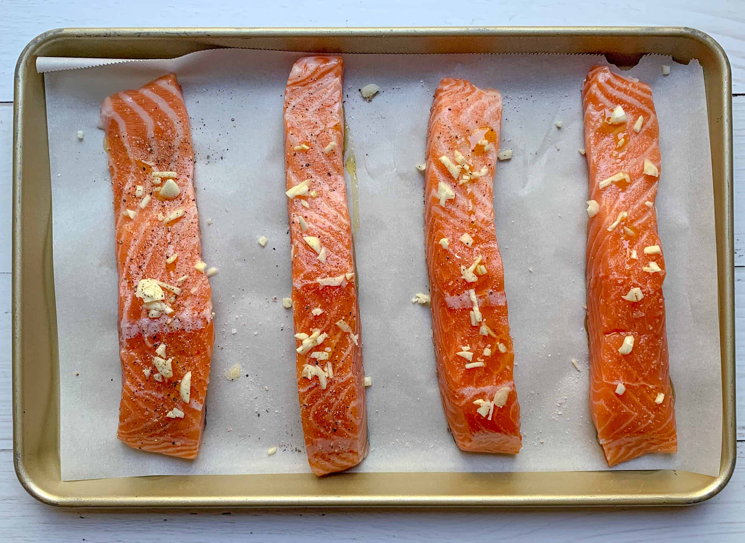 4 uncooked fillets of salmon on parchment paper lined baking sheet 