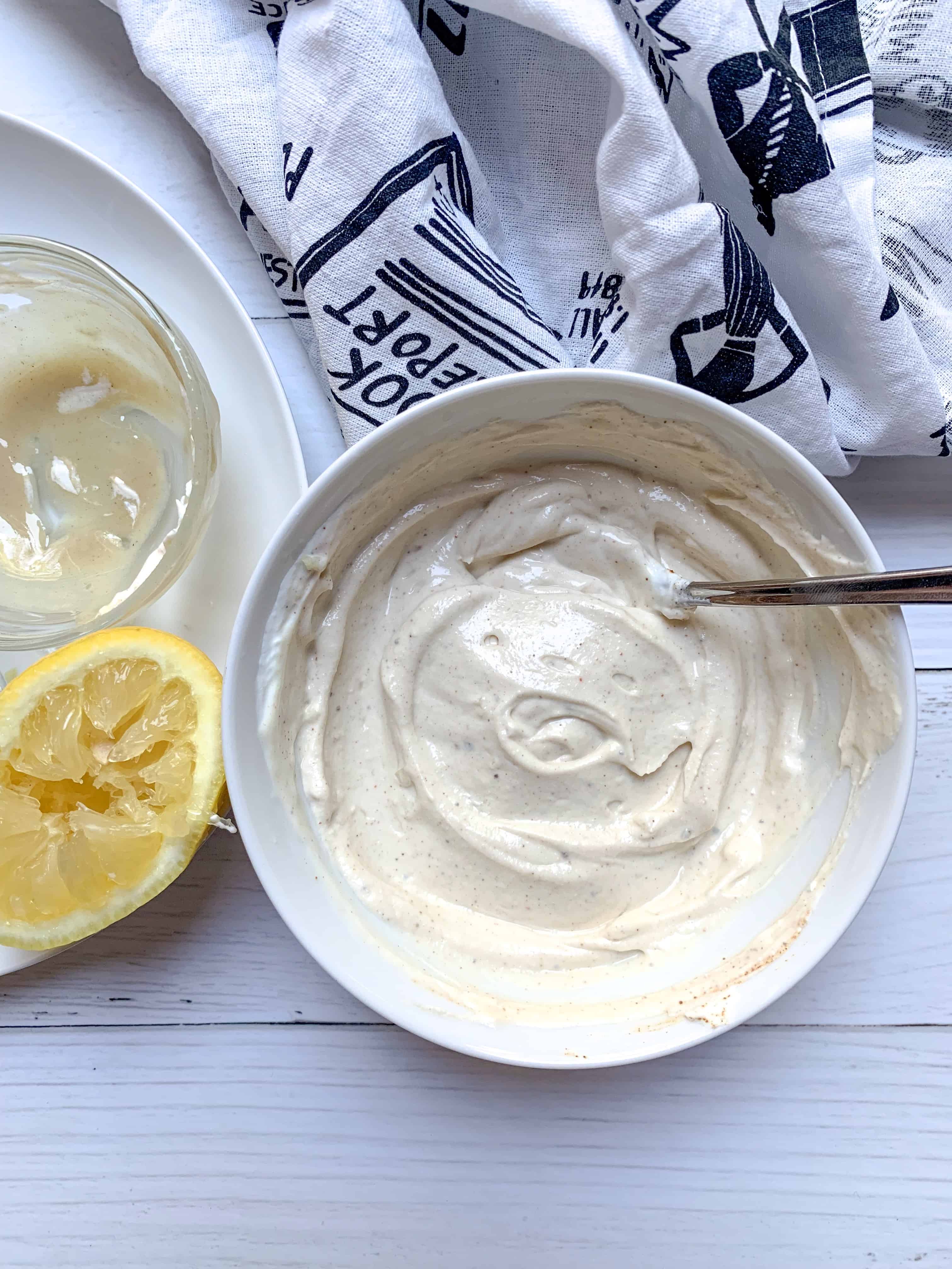 bowl with yogurt tahini dressing with squeeze of lemon next to it.