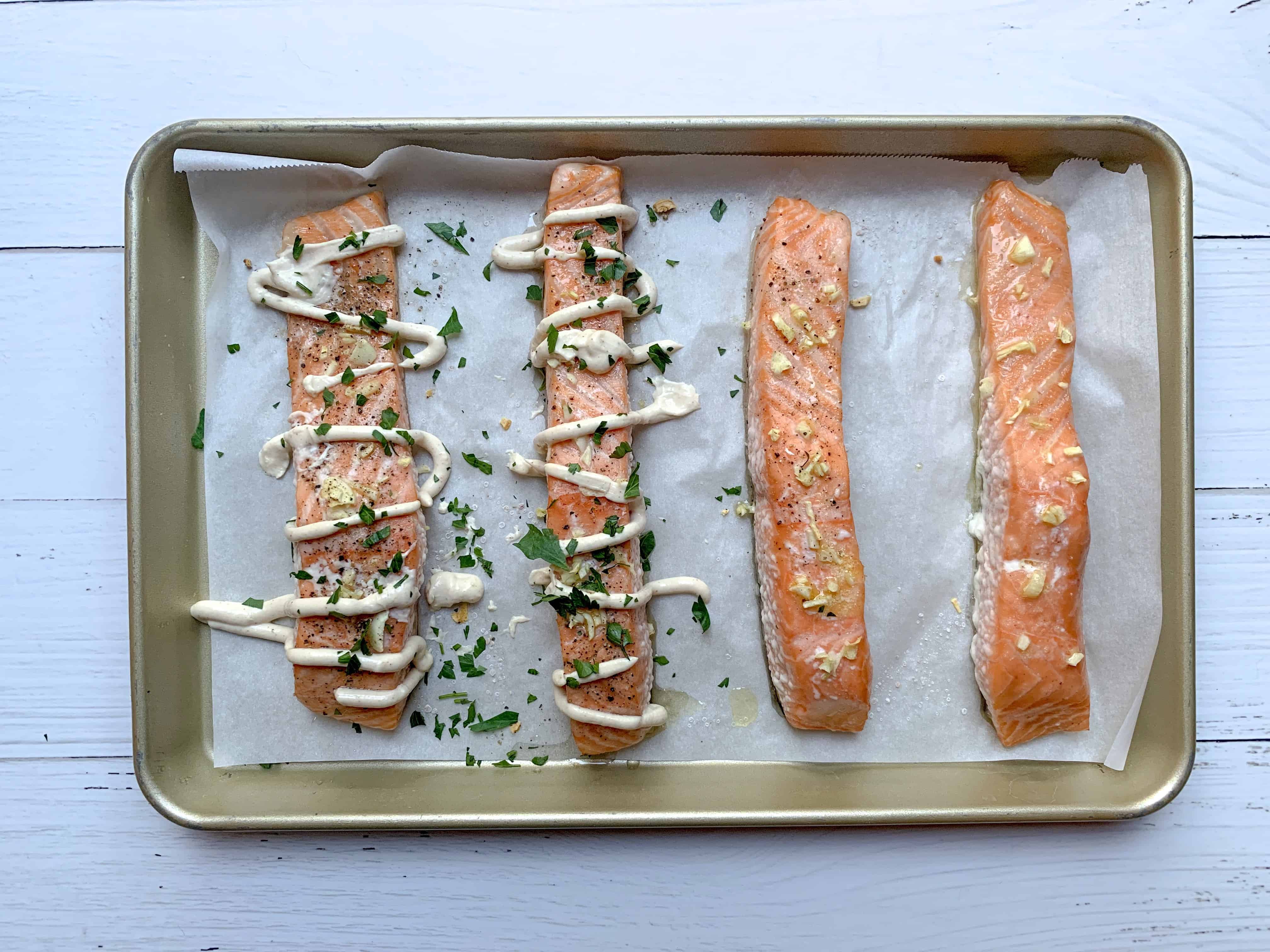 4 fully cooked salmon fillets, two of them are drizzled with yogurt tahini and parsley.