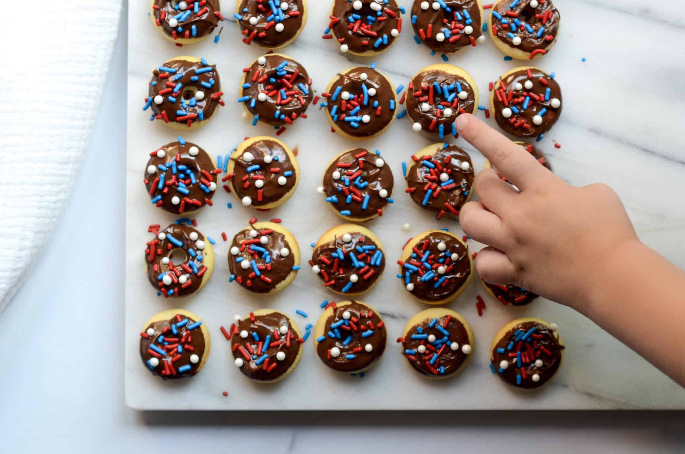 little hand touching mini baked donuts