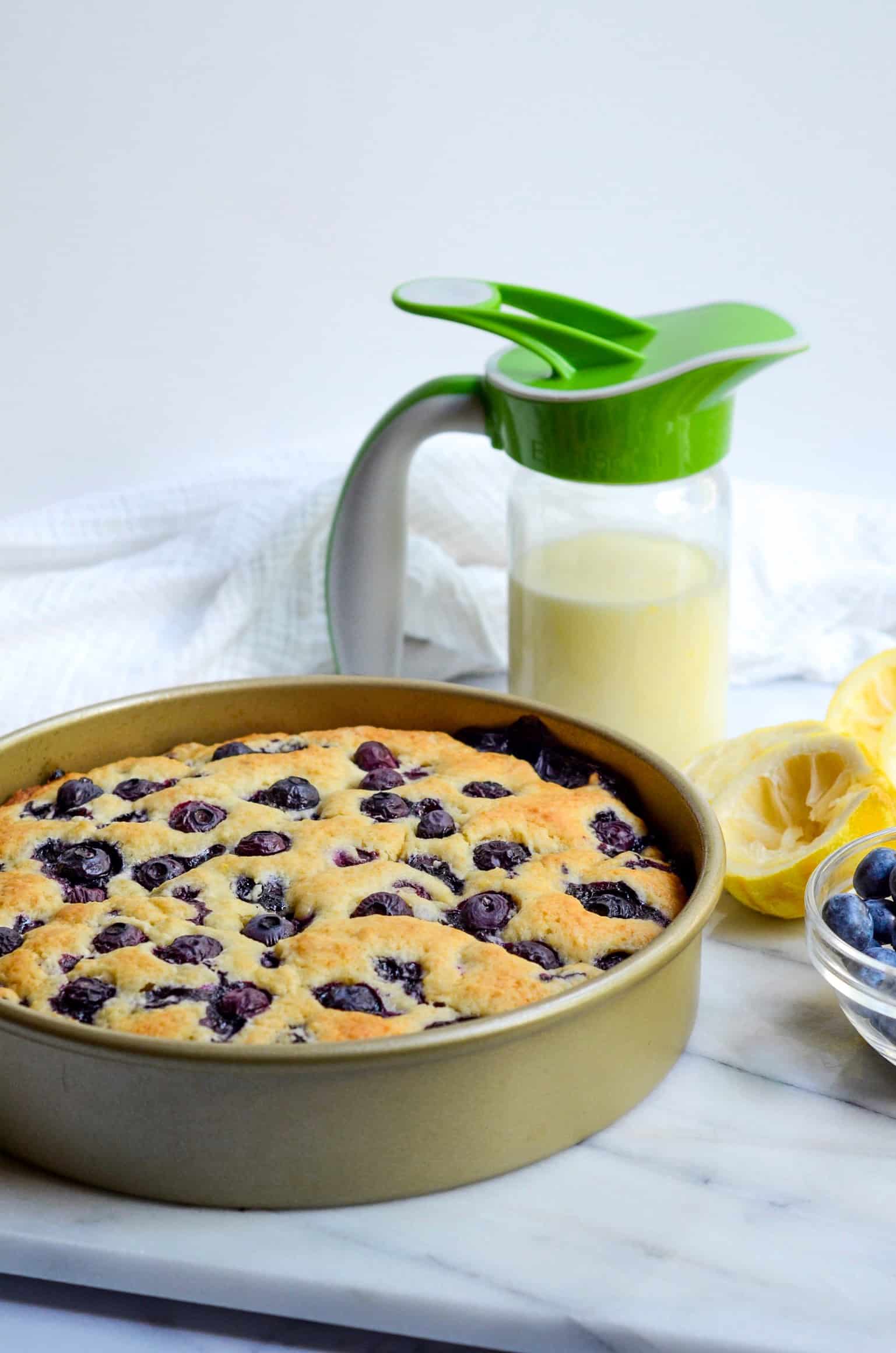 blueberry breakfast cake resting in a gold, round pan. 