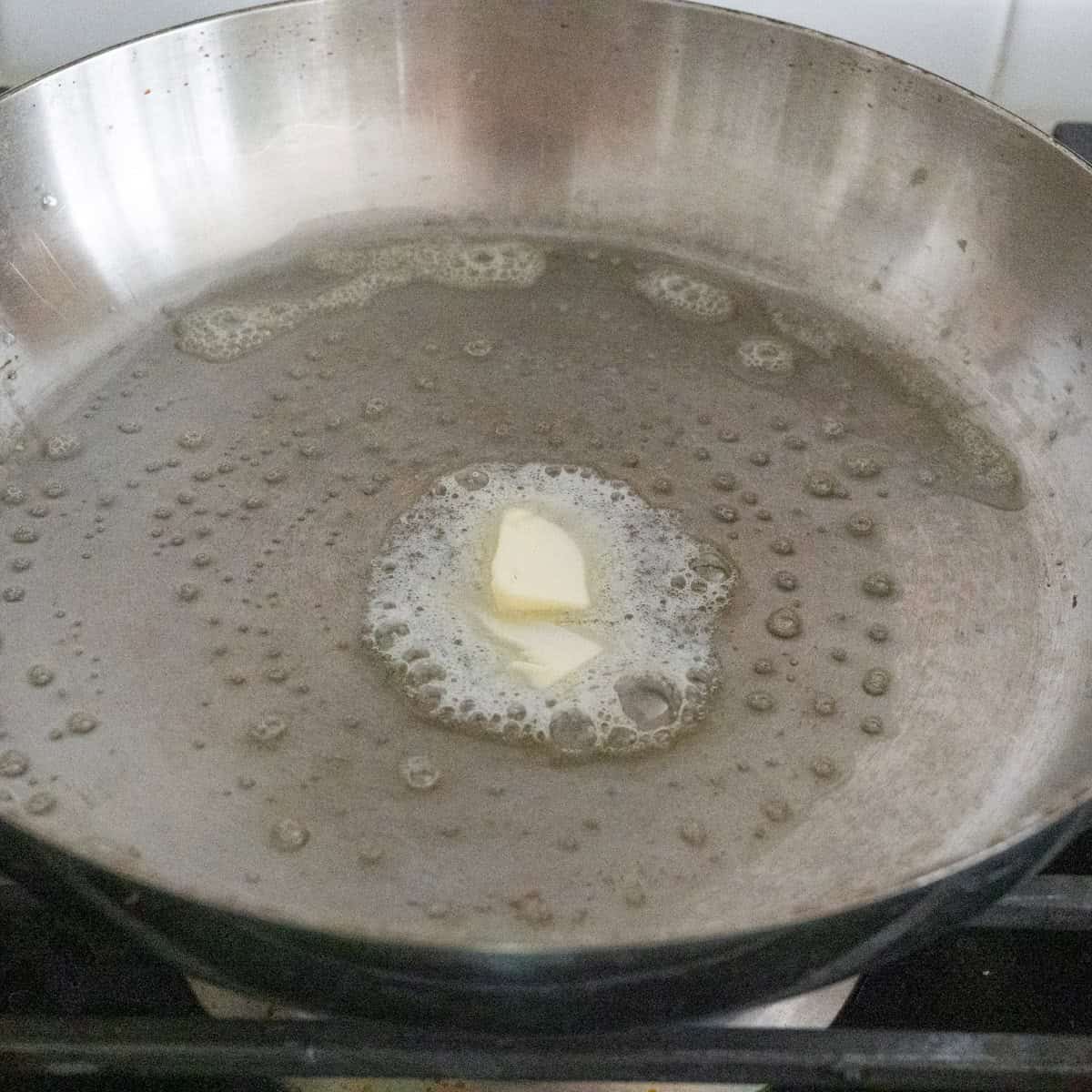 Step 3 of directions showing a slab of melted butter in a stainless steel pan.