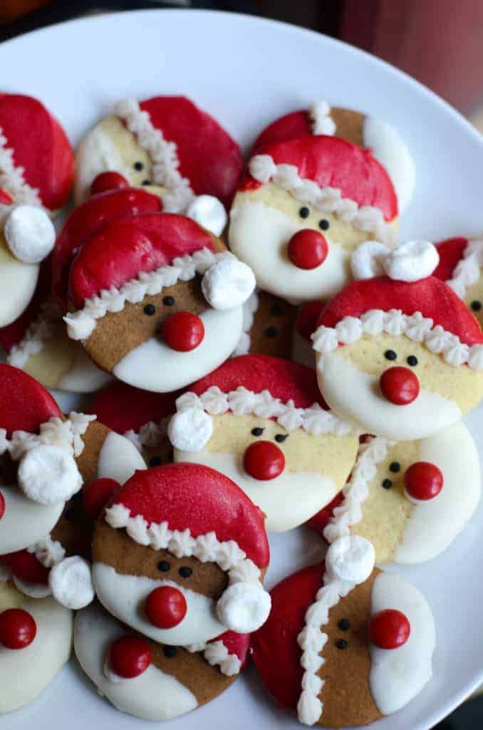 a pile of santa sugar cookies on a white plate.