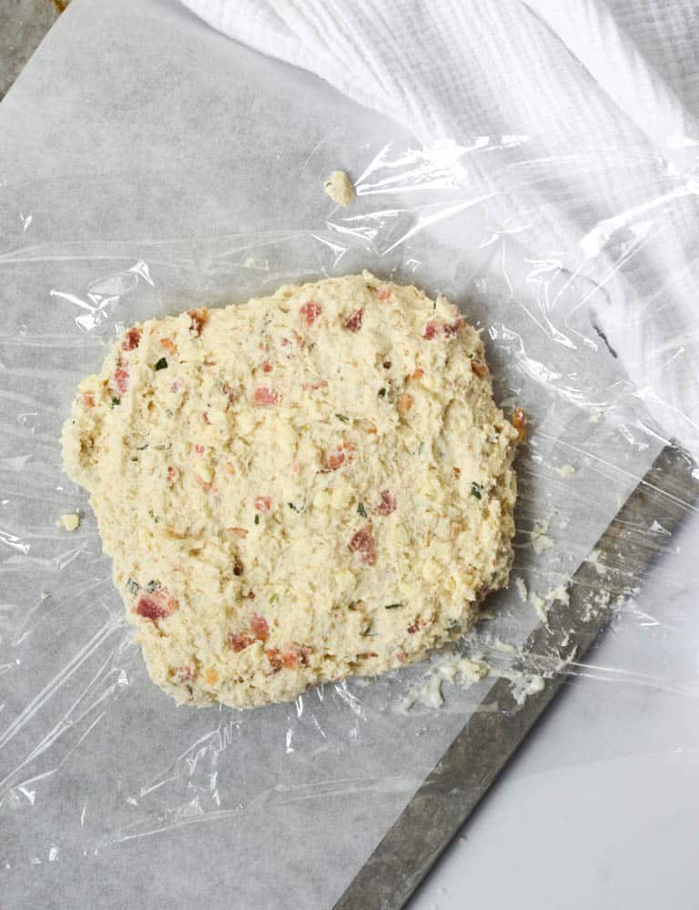 ball of dough on plastic wrap on top of baking sheet. 