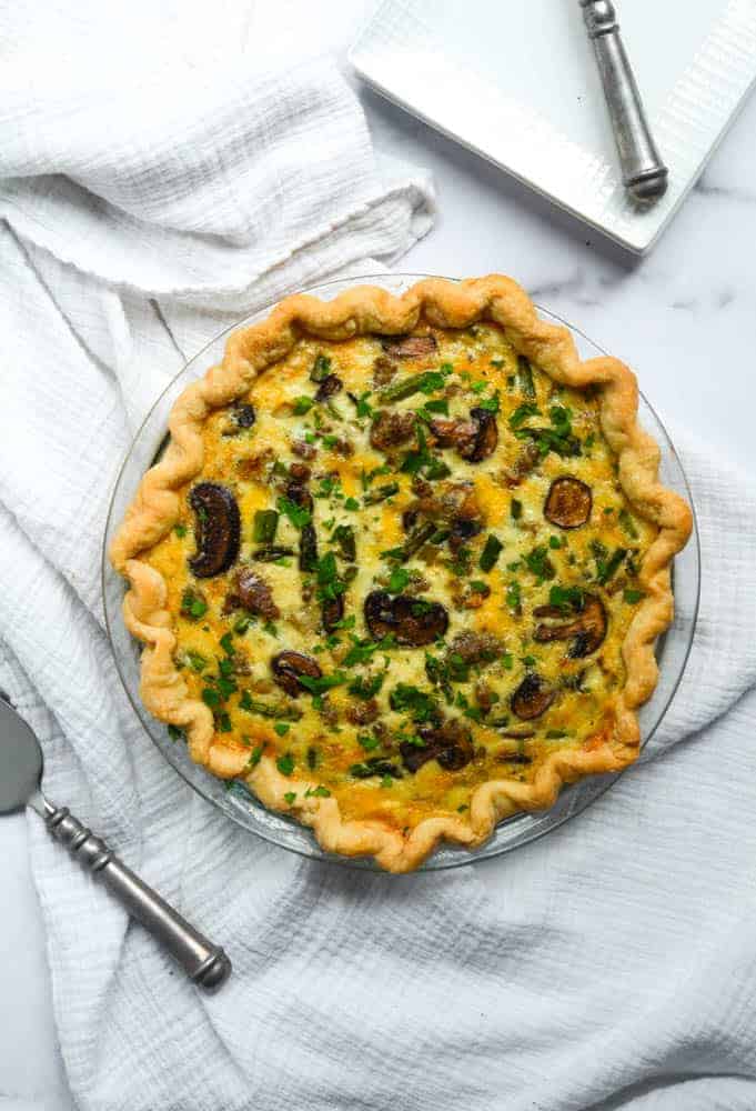 aerial view of quiche over white cloth and pie server. 