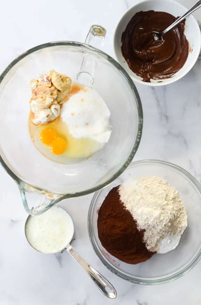 3 bowls and 1 measuring cup full of ingredients needed for gluten free chocolate donuts