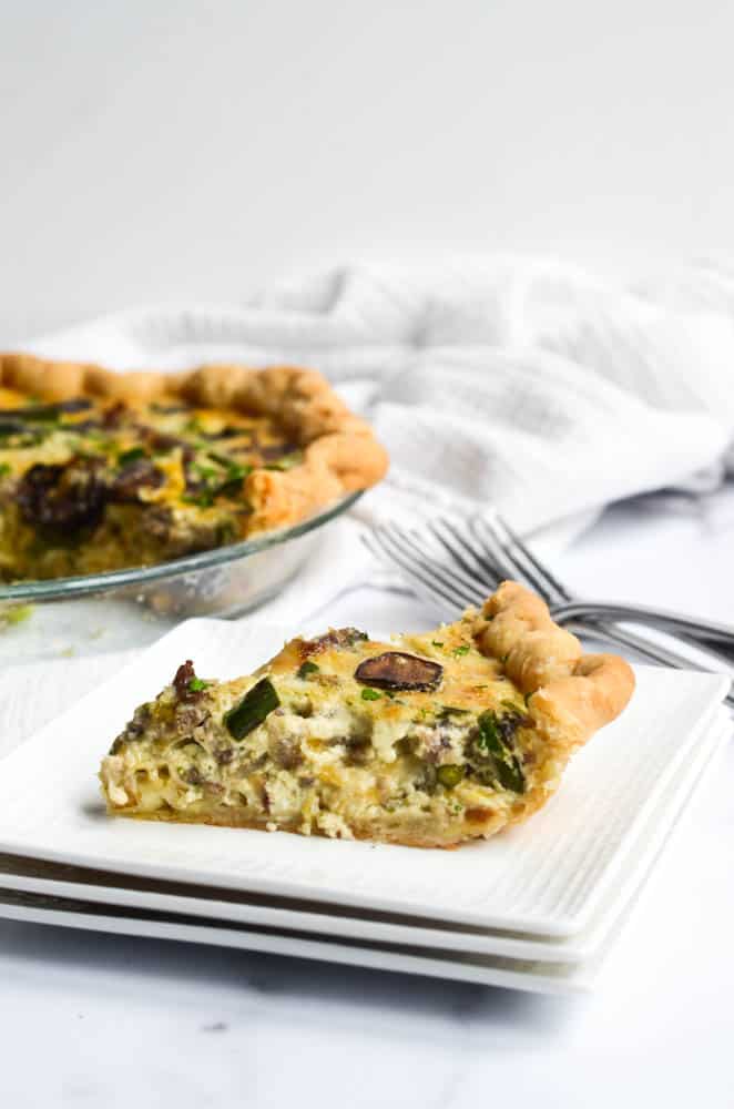 side view of slice of quiche with whole quiche in the background