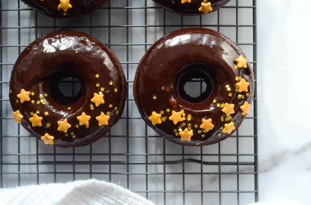 up close shot of two chocolate donuts on cooling tray 