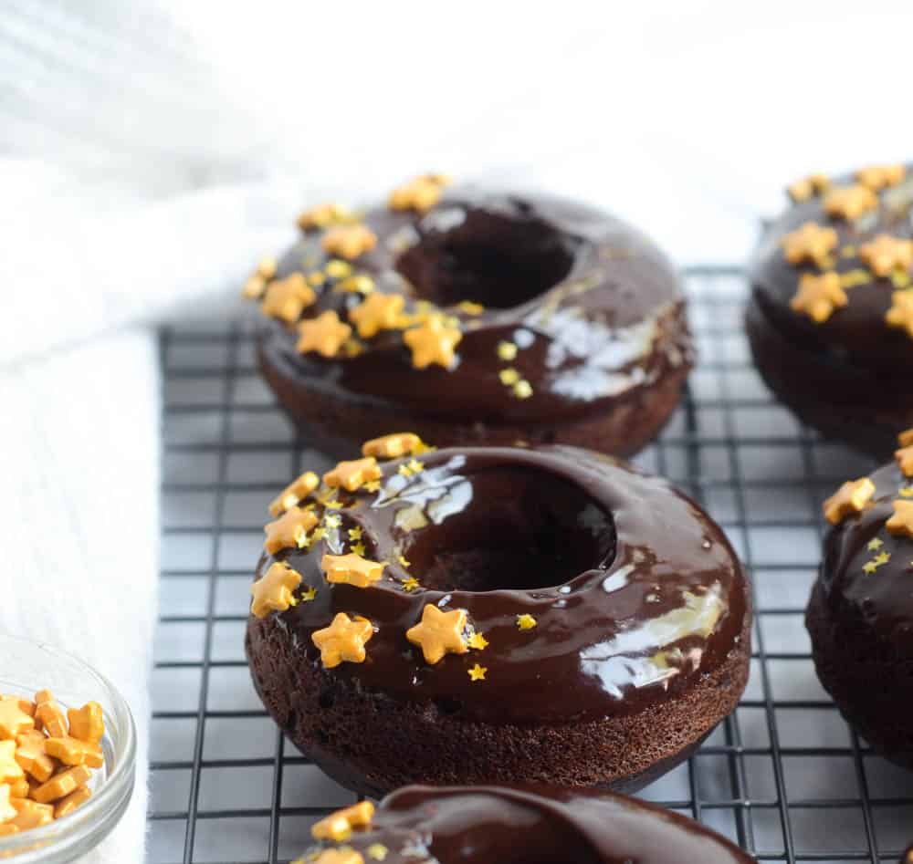 side view of donuts covered in chocolate ganache and decorated with gold star sprinkles