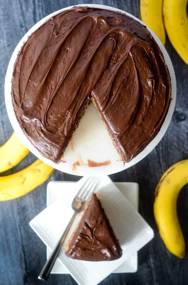 one slice on plate in background with rest of cake in the focus. bananas in background