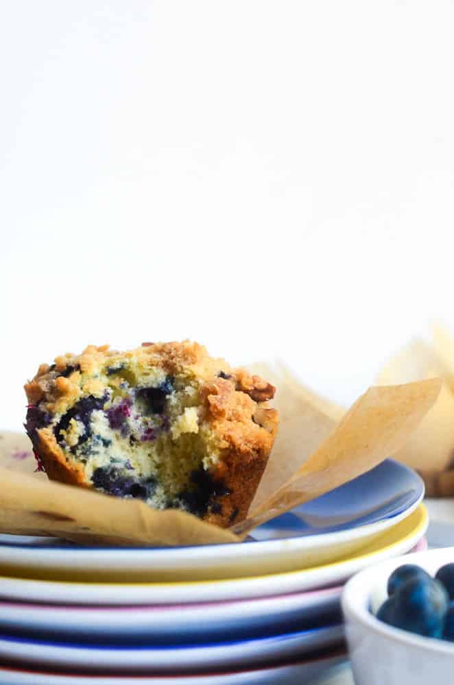 blueberry muffin bitten into and on top of stacked colorful plates