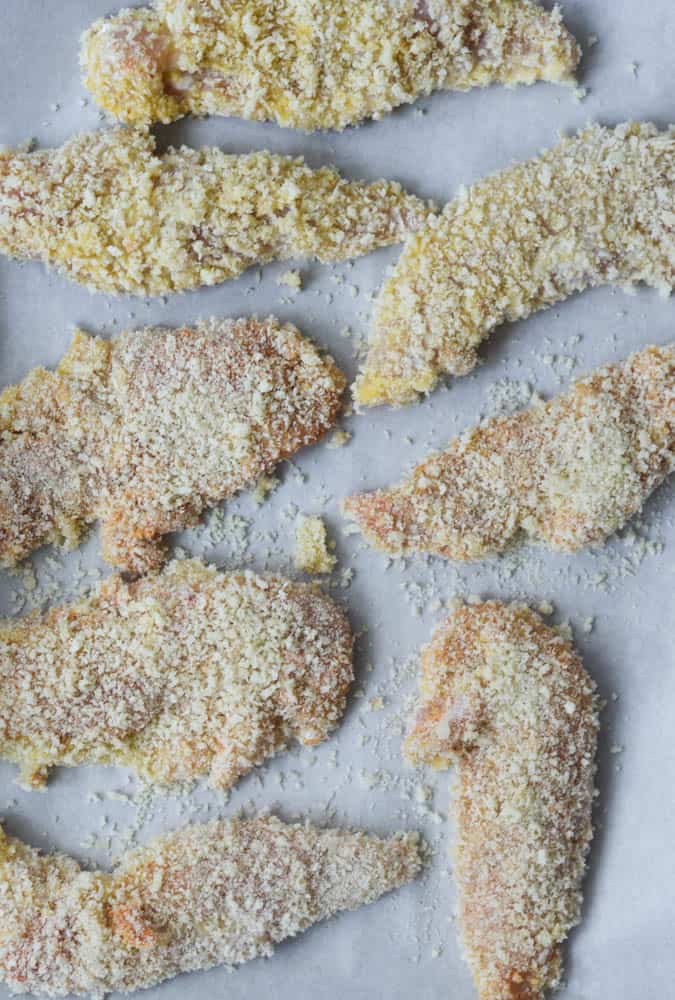 aerial view of chicken tenders on baking sheet once they're coated