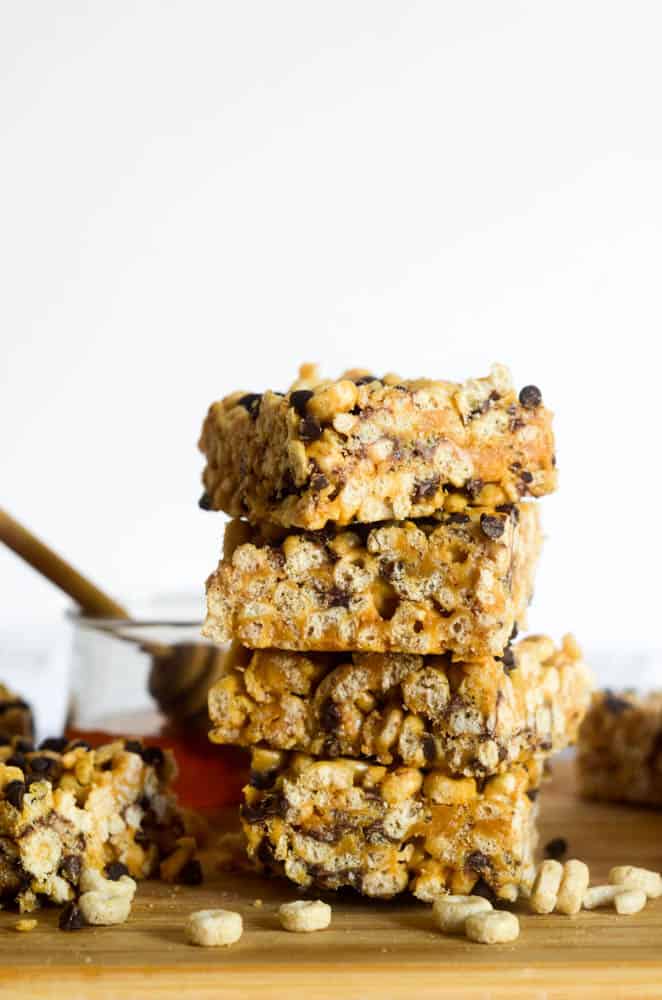 homemade cereal bars stacked on one another with honey in the background
