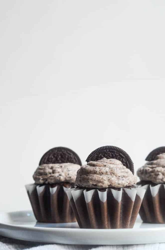 up close picture of 3 chocolate cupcakes with oreo frsoting and oreo on top