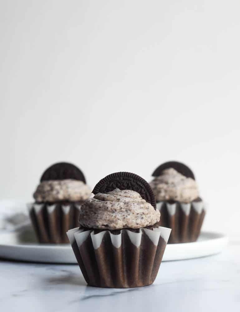 frosted cupcake in foreground with two other cupcakes in background