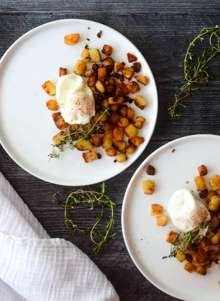 aerial shot of two white plates with southern fried potatoes and sprigs of thyme around plate