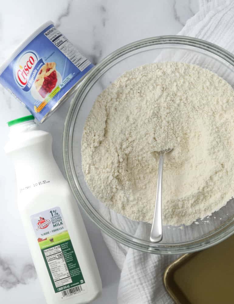 bowl of flour with container of crisco and quarter of buttermilk 