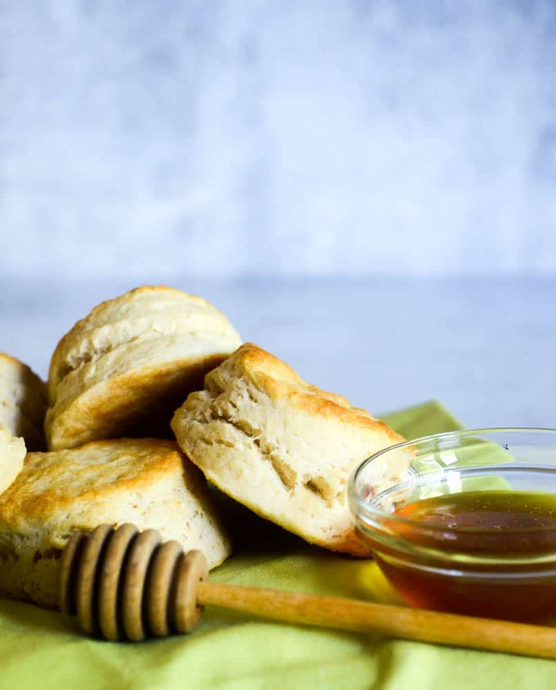 southern buttermilk biscuits stacked on top of one another next to bowl of honey