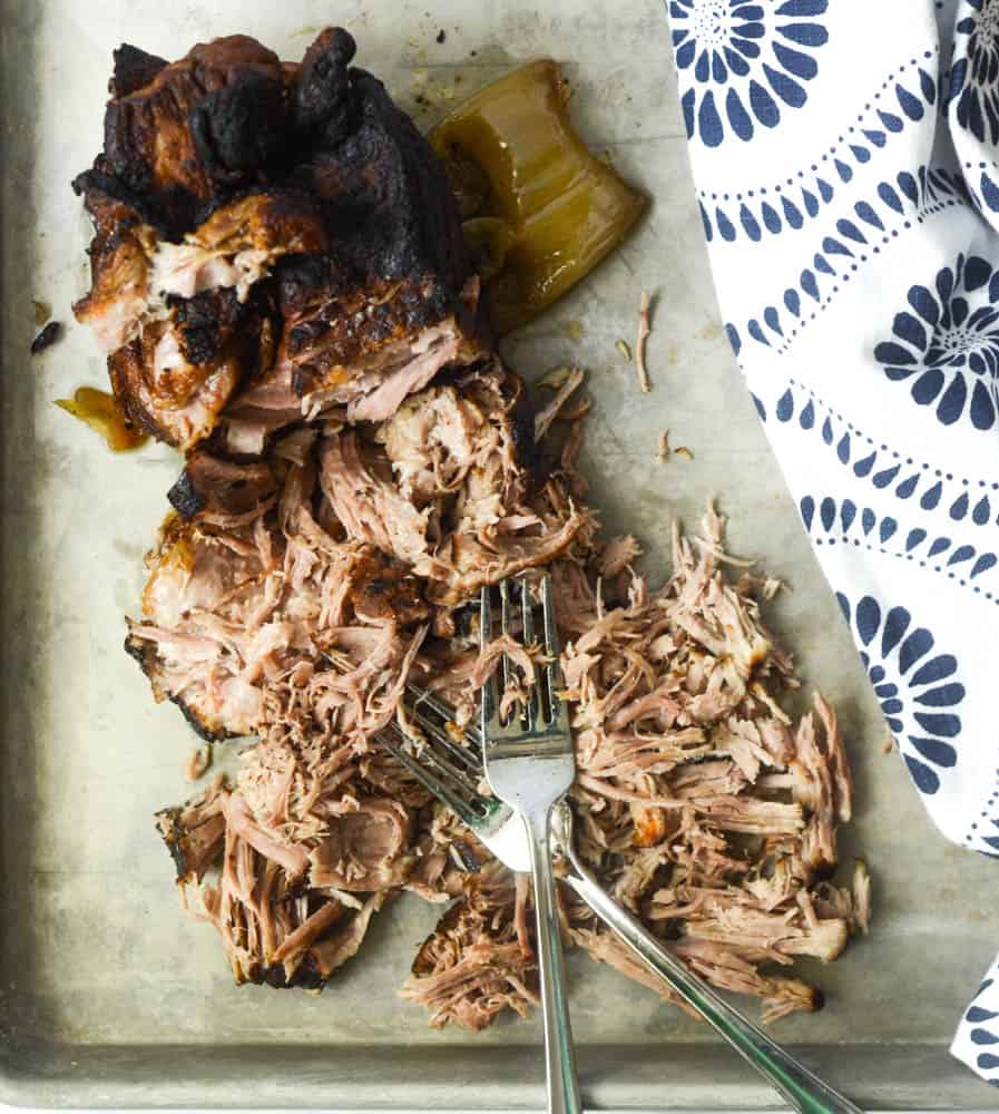 aerial view of shredded pulled prok with two forks and blue and white napkin