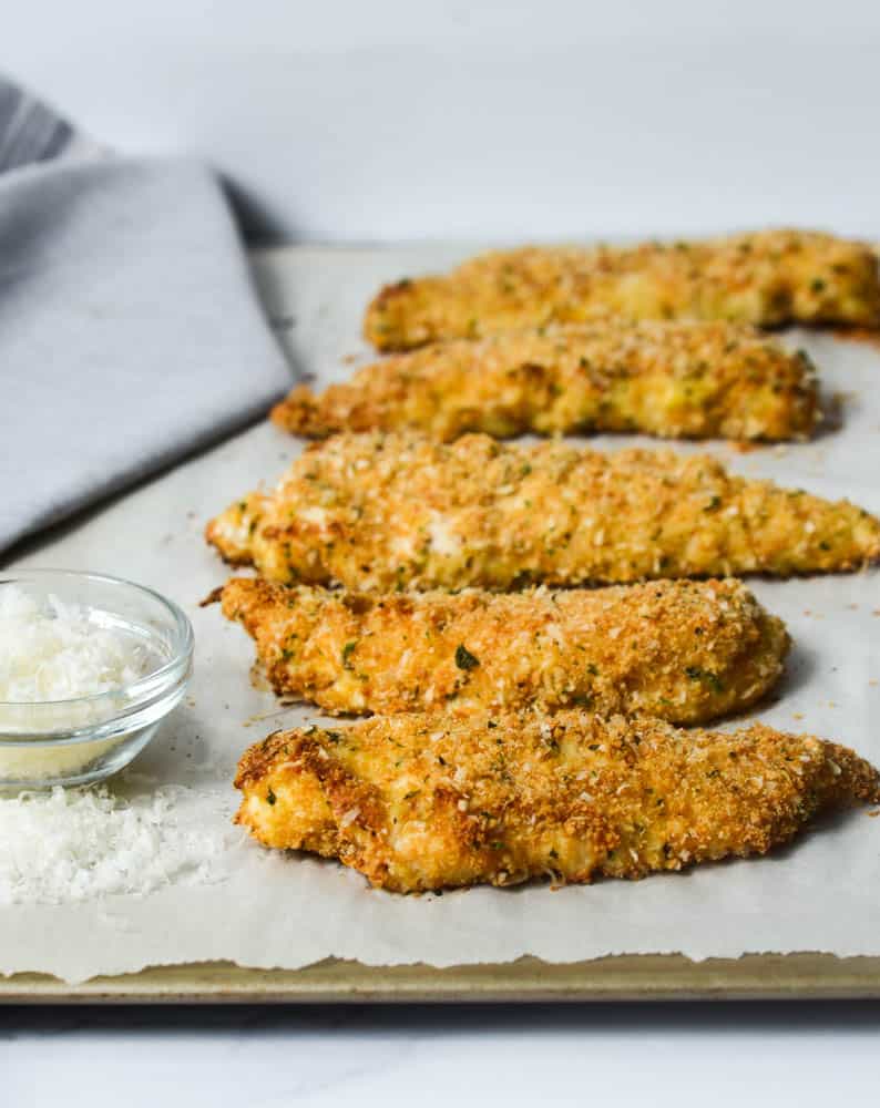 side view of chicken tenders on baking sheet lined with parchment paper 