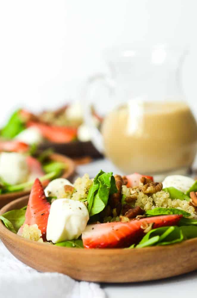 close up of strawberries and mozzarella balls on a plate of salad