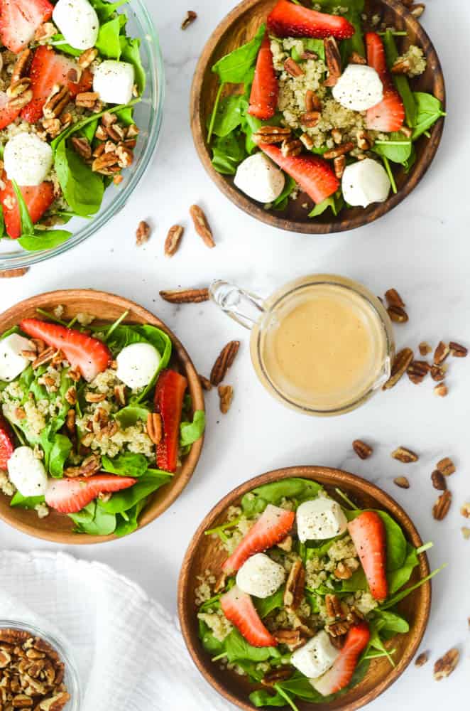 aerial view of three plates of strawberry caprese salad on granite background with pecans strewn about