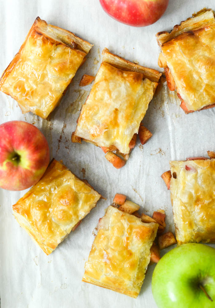 flat lay of cut apple slab pie with apples scattered. 