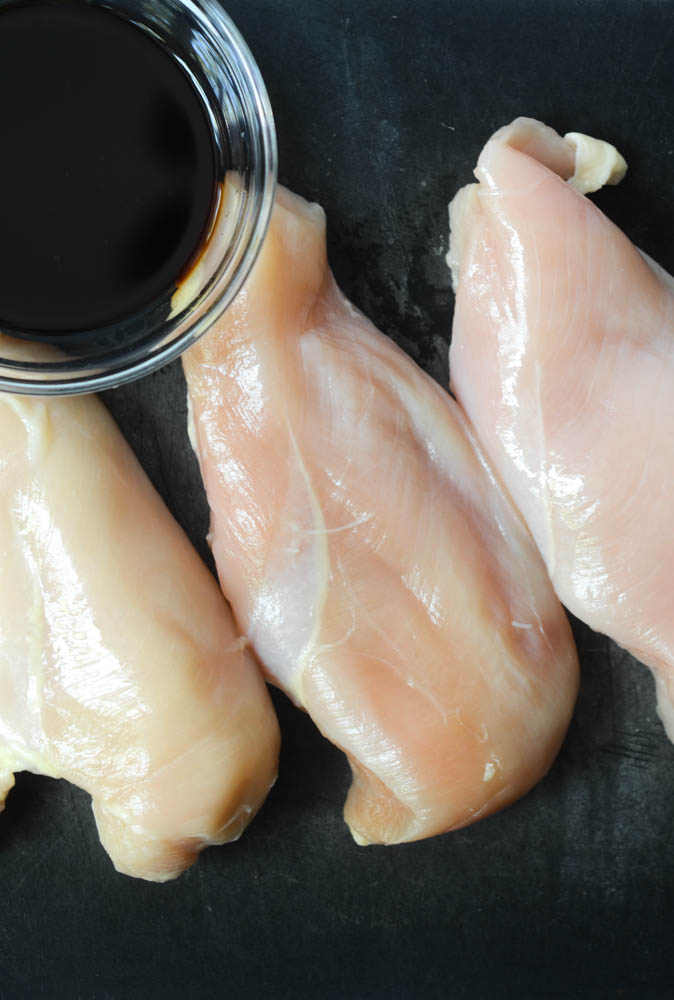 overhead shot of chicken breasts on black cutting board 