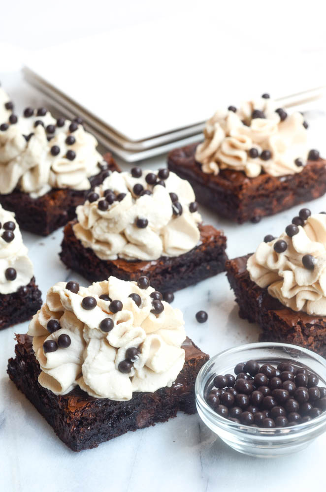 6 frosted brownies on marble tray with chocolate nibs on glass bowl