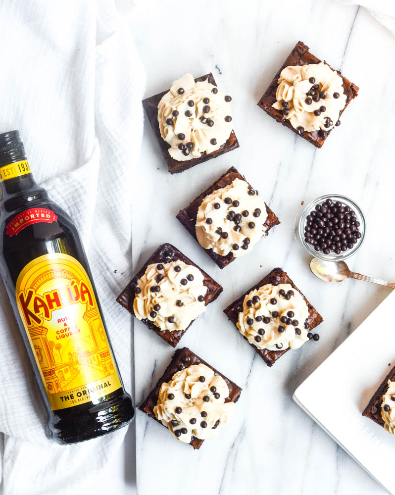 aerial shot of frosted brownies with chocolate bits in bowl and bottle of kahlua