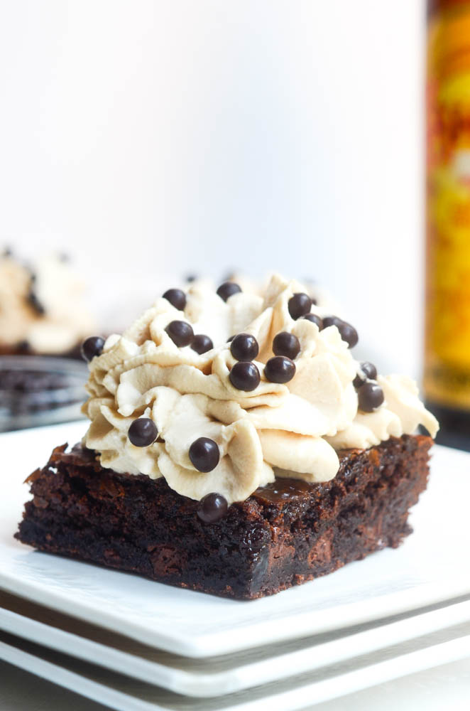 close up of brownie with frosting on white plate and chocolate nibs