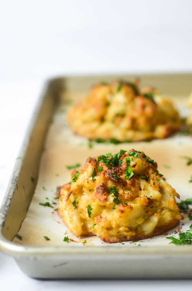 side view of fully baked crab cake on baking sheet with parsley on top