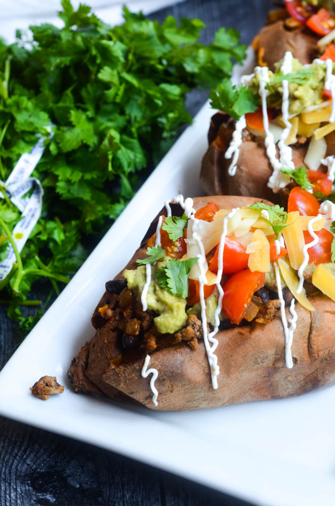 close up of one taco stuffed sweet potato with toppings and sour cream