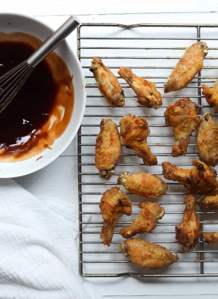 crispy cooked chicken wings on wire rack before being coated with BBQ sauce.