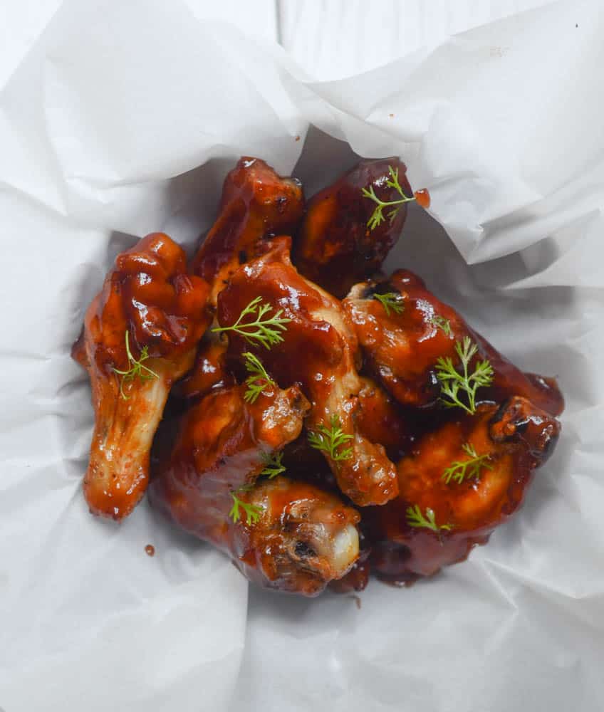 BBQ chicken wings ina. bowl topped with fresh parsley.