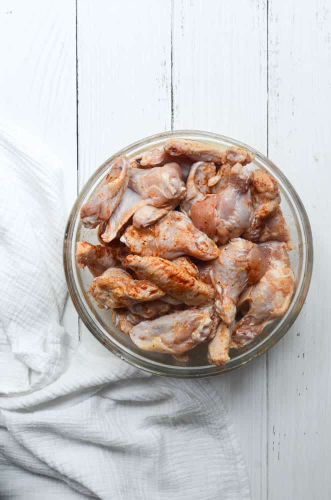 bowl o raw chicken wings coated in seasonings. 