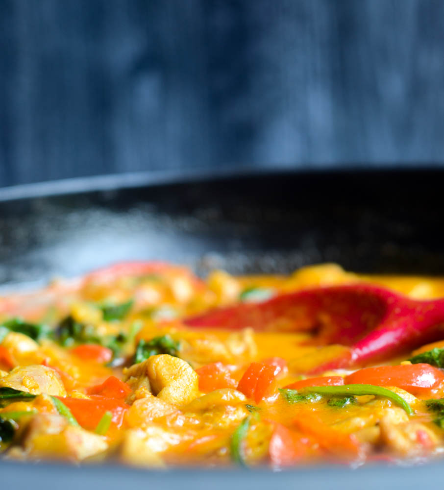 close up side view of curry being stirred by red spatula 