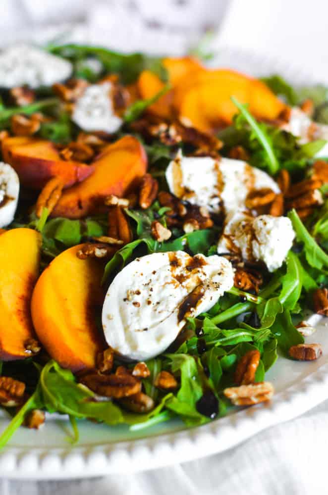 up close picture of burrata on peach salad drizzled with balsamic glaze 