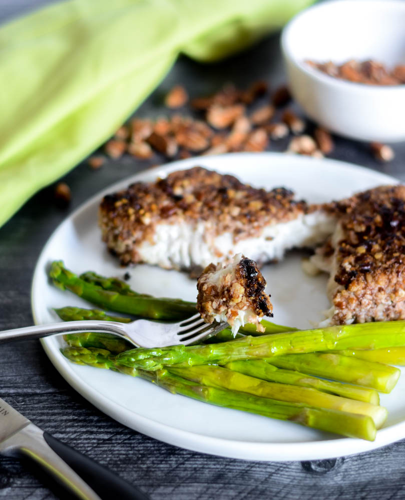 photo of one bite of fish in focus on a fork while the rest of the dinner remains in background. 