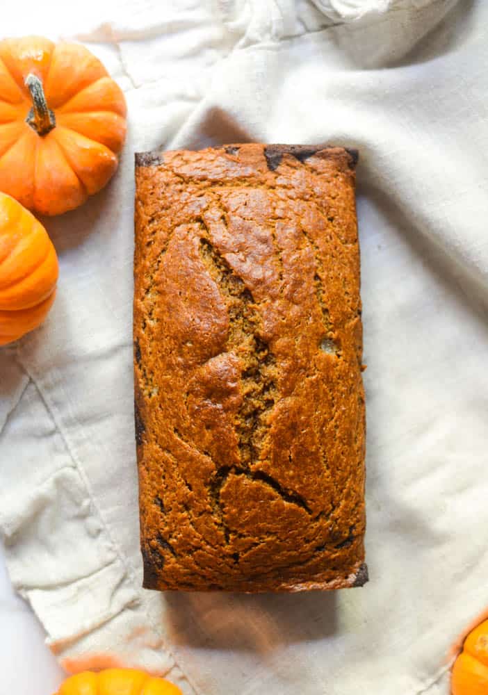 aerial pic of full pumpkin loaf on burlap hand towel with mini pumpkins around.