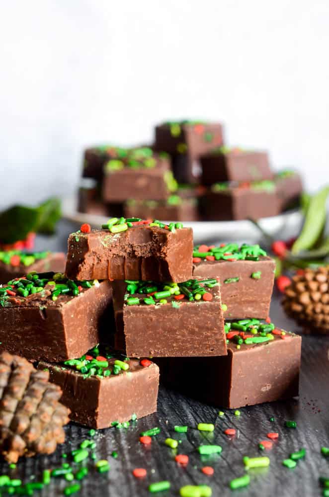 chocolate fudge stacked up in a pyramid. top square of fudge is bitten into exposing teeth marks. 