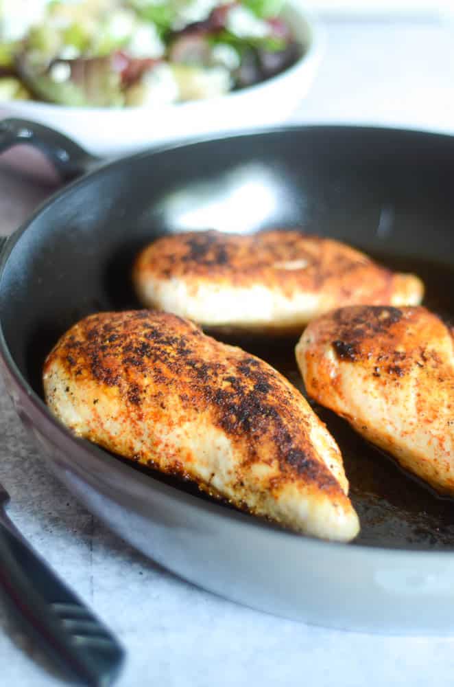 close up picture of one cooked chicken breast in cast iron skillet.