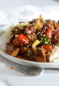 close up of white plate with pineapple chicken over rice.
